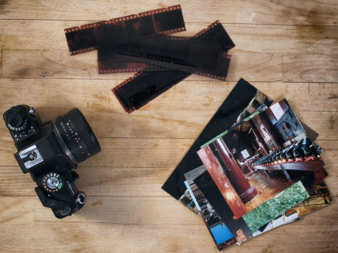 camera film and photos on wooden background